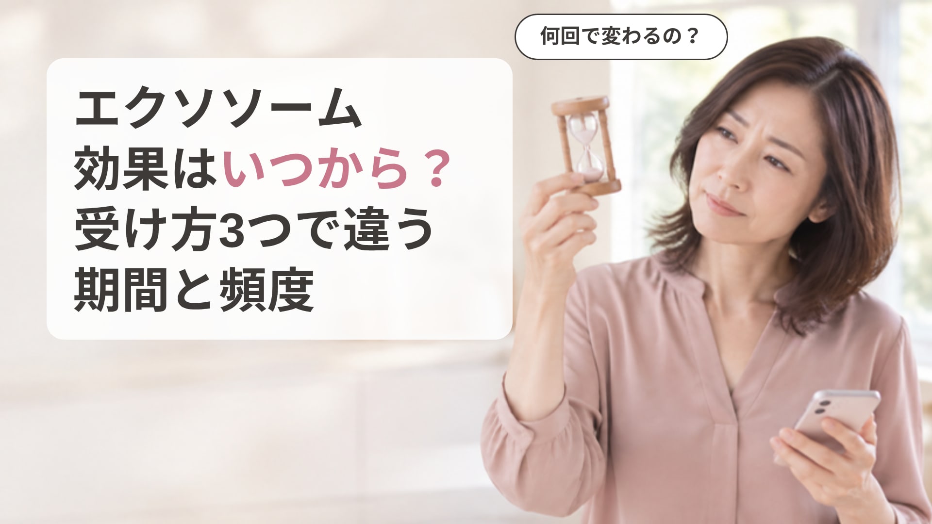 キッチンで砂時計を目の高さに持ち上げ、スマホを手に、効果がいつ出るのか迷った表情を浮かべている50代の女性の画像